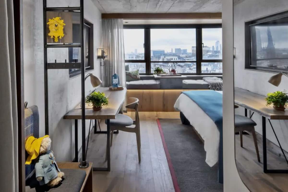 Una habitación de hotel moderna con vista a la ciudad, un sofá, un escritorio y una cama.