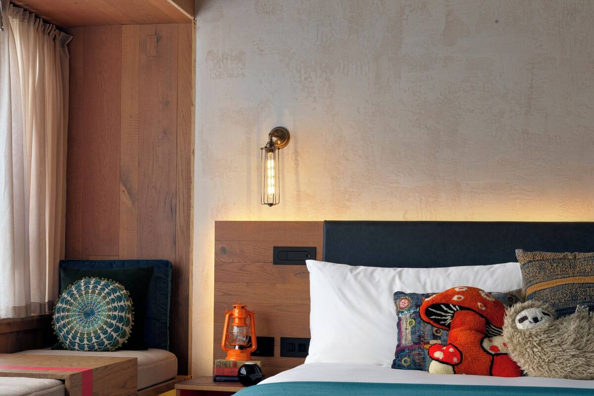 A bedroom with a wooden headboard, a bed with a teal bedspread, a plush toy, and a decorative pillow.