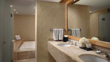 Une salle de bain avec une baignoire, deux lavabos, un miroir et des serviettes.