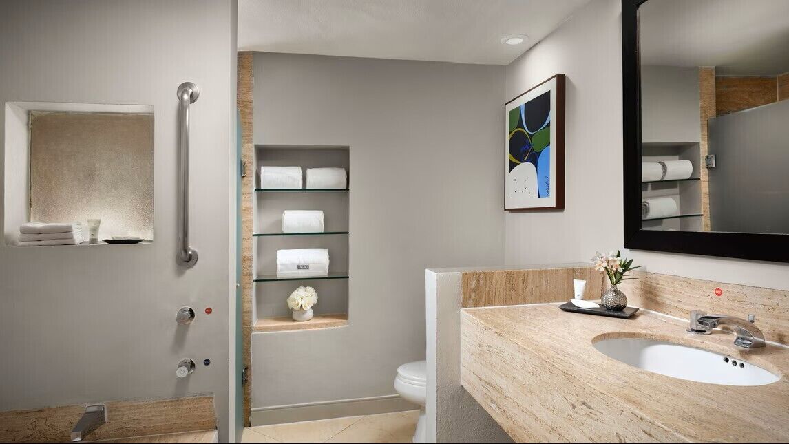 Une salle de bain moderne avec une douche à l’italienne en verre, un meuble-lavabo en bois et un grand miroir.