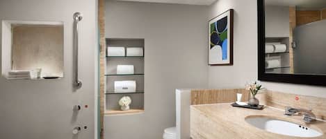 Une salle de bain moderne avec une douche à l’italienne en verre, un meuble-lavabo en bois et un grand miroir.
