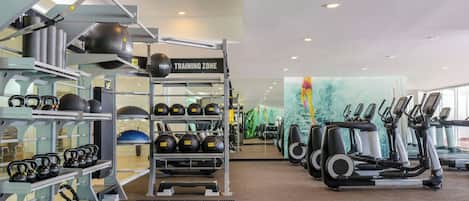 A gym with kettlebells, medicine balls, and treadmills.