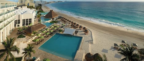 A resort with a swimming pool, beach, and ocean view.