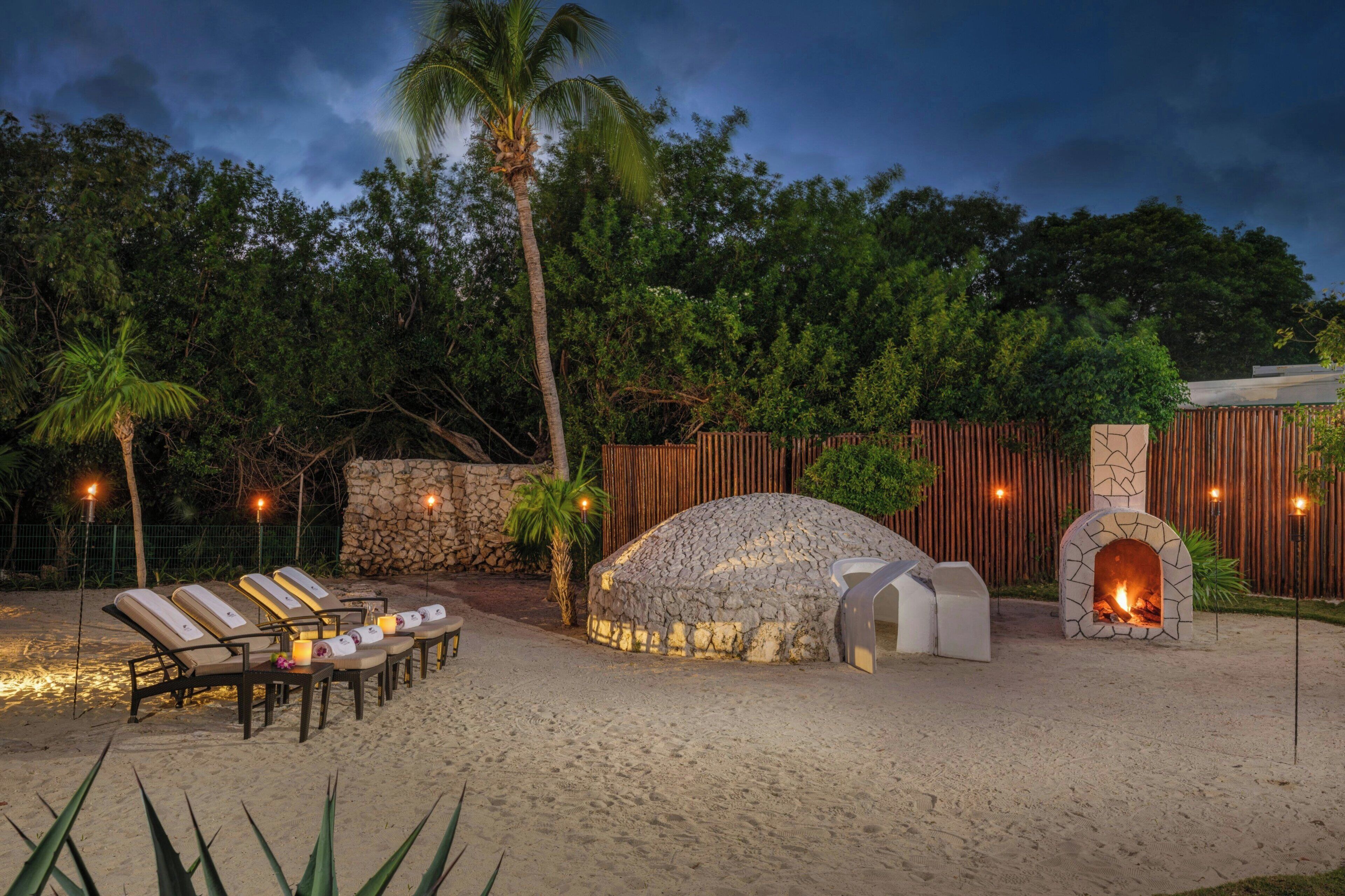 An outdoor seating area with lounge chairs and a stone oven.