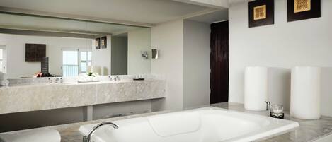 A modern bathroom with a large bathtub, a double vanity with a mirror, and a dark wooden door.