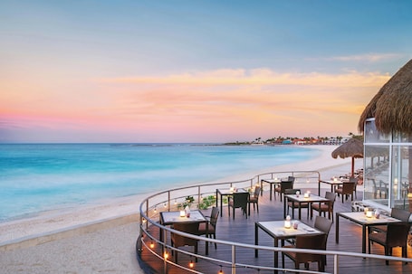 A seaside restaurant with outdoor seating overlooking the ocean.