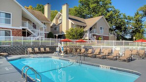 A swimming pool with a white fence, lounge chairs, and umbrellas. - Residence Inn By Marriott Binghamton (Vestal)