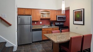A compact kitchen with a refrigerator, microwave, stove, and a dining table with chairs. - Residence Inn By Marriott Binghamton (Vestal)