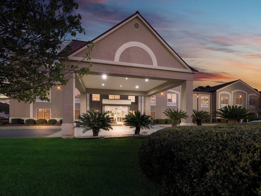 A hotel with a covered entrance, multiple windows, and a well-maintained lawn.