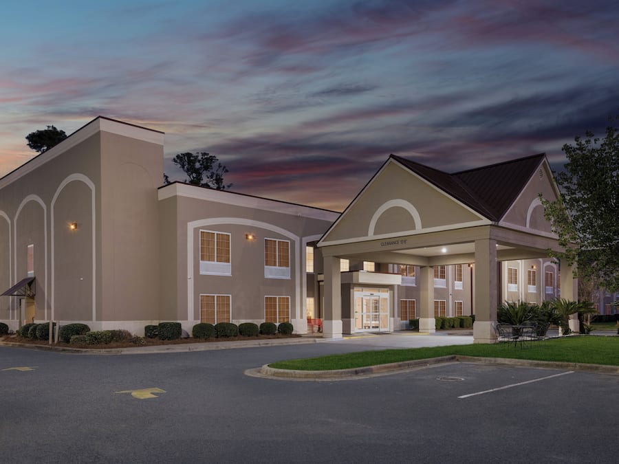 A hotel with a covered entrance, multiple windows, and a parking lot.