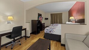 A hotel room with a desk, chair, bed, and a sofa. - Red Roof Inn & Suites Albany, GA (Albany)
