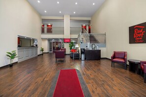 A hotel lobby with a red carpet, a staircase, and a sign indicating free Wi-Fi in all rooms. - Red Roof Inn & Suites Albany, GA (Albany)