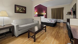 Une chambre d’hôtel avec un canapé, un lit, un bureau et une télévision.