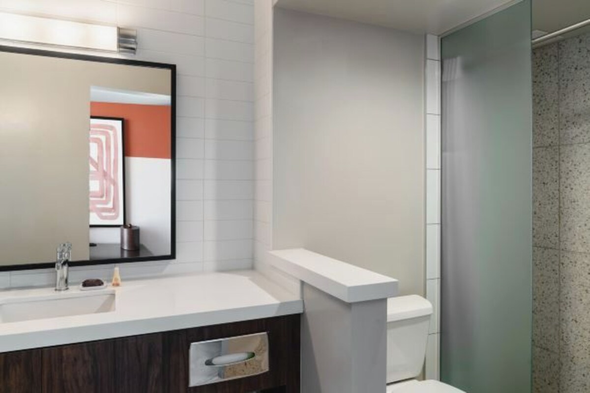 A bathroom with a white sink, mirror, and toilet.