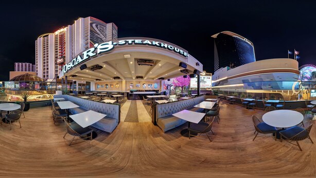 A large, modern steakhouse with a curved roof and multiple seating areas, including booths and tables, set against a city skyline at night. - Plaza Hotel & Casino (Las Vegas)