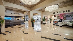 A spacious indoor area with a registration desk, a coffee bar, and a gelato display. - Plaza Hotel & Casino (Las Vegas)