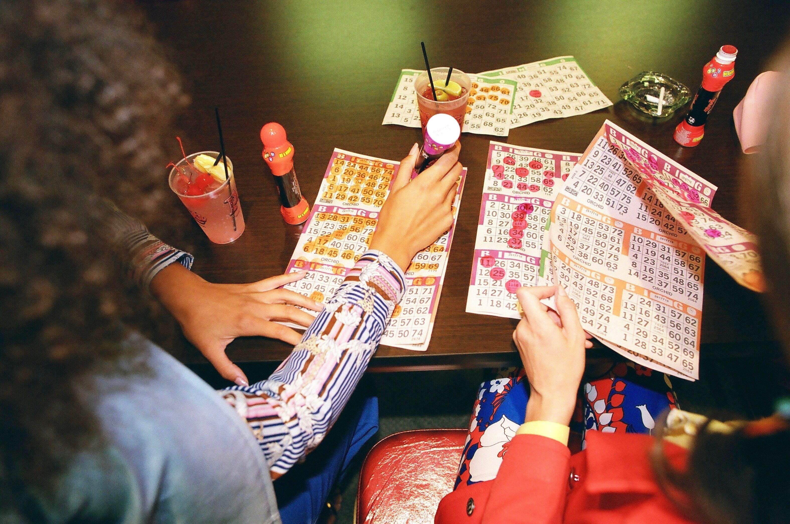 Un grupo de personas jugando al bingo, con tarjetas y bebidas sobre una mesa.