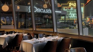A restaurant with tables set for dining, a view of the street outside, and a neon sign for Oscar's. - Plaza Hotel & Casino (Las Vegas)