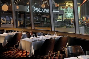 Ein Restaurant mit gedeckten Tischen und Blick auf die Straße, mit einem Neon-Schild für Oscar's.