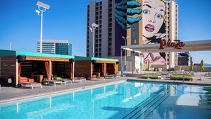 A swimming pool with lounge chairs and a building with a large mural in the background. - Plaza Hotel & Casino (Las Vegas)