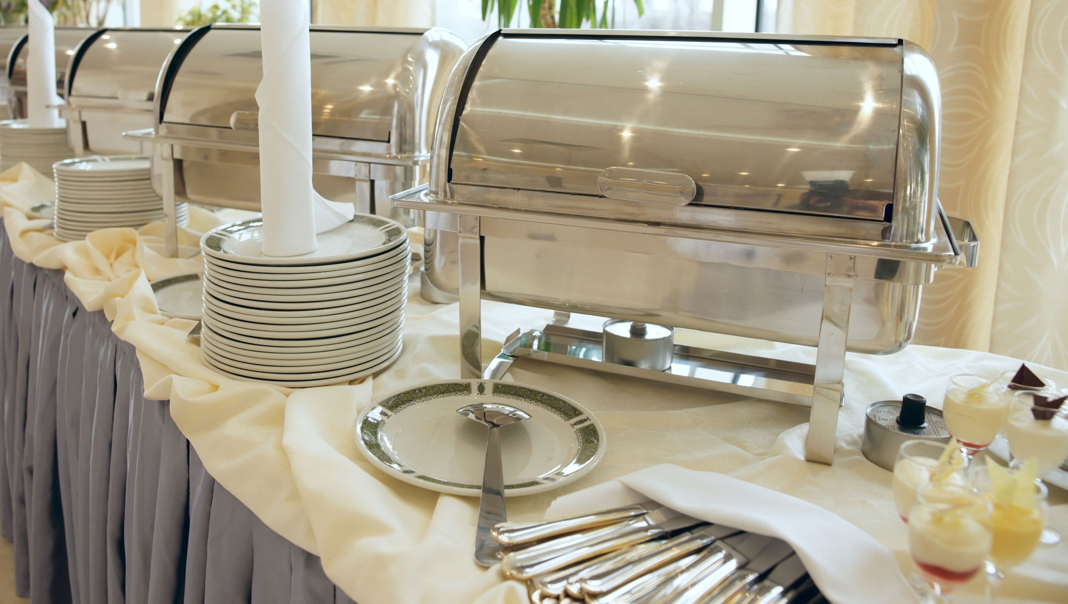 Een buffetopstelling met meerdere zelfbedieningsfood stations, inclusief een drankdispenser en diverse bestek.