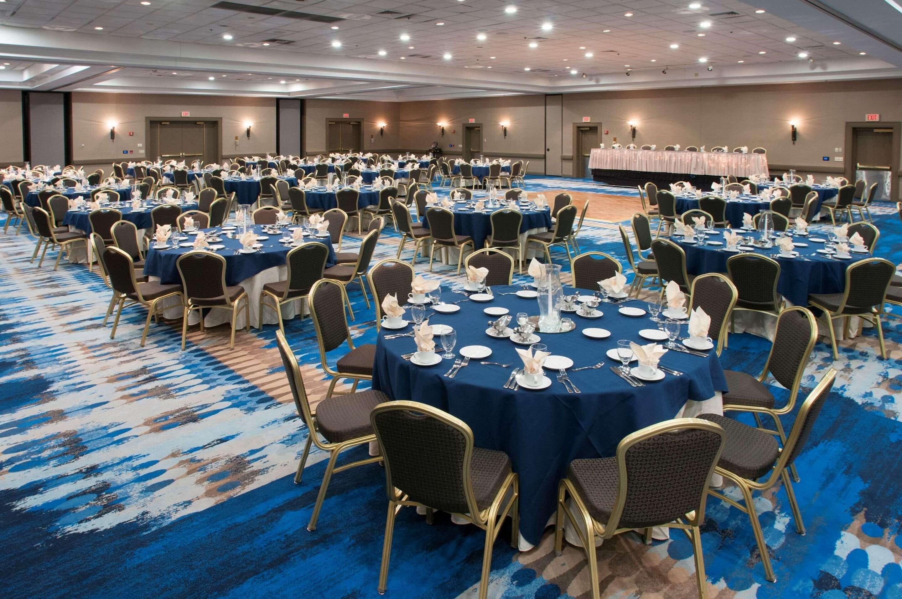 A large banquet hall with round tables set for dining, equipped with chairs and table settings.