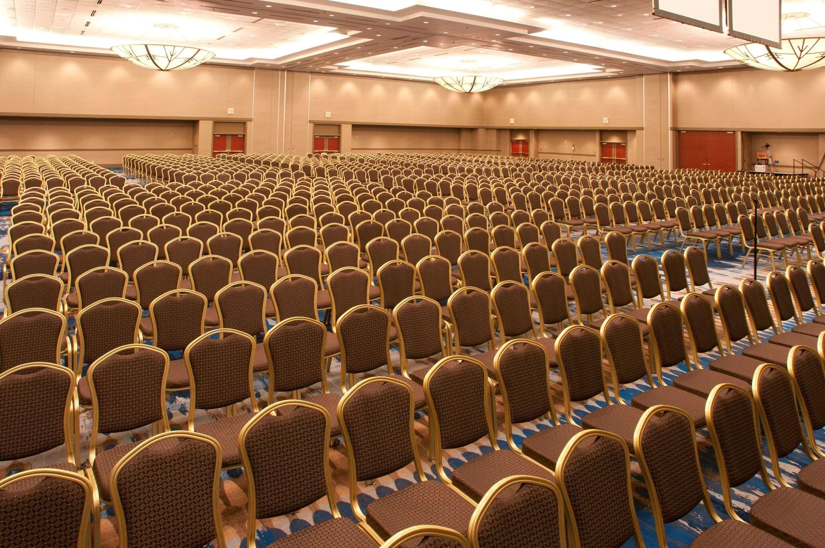 A large conference room with rows of chairs and a stage.
