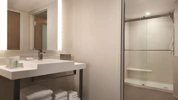 A modern bathroom with a white sink, mirror, and glass shower enclosure.