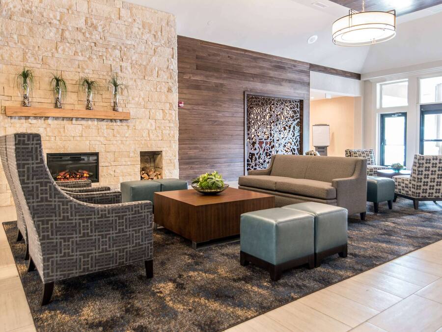 A modern living room with a stone fireplace, comfortable seating, and a decorative wall panel.
