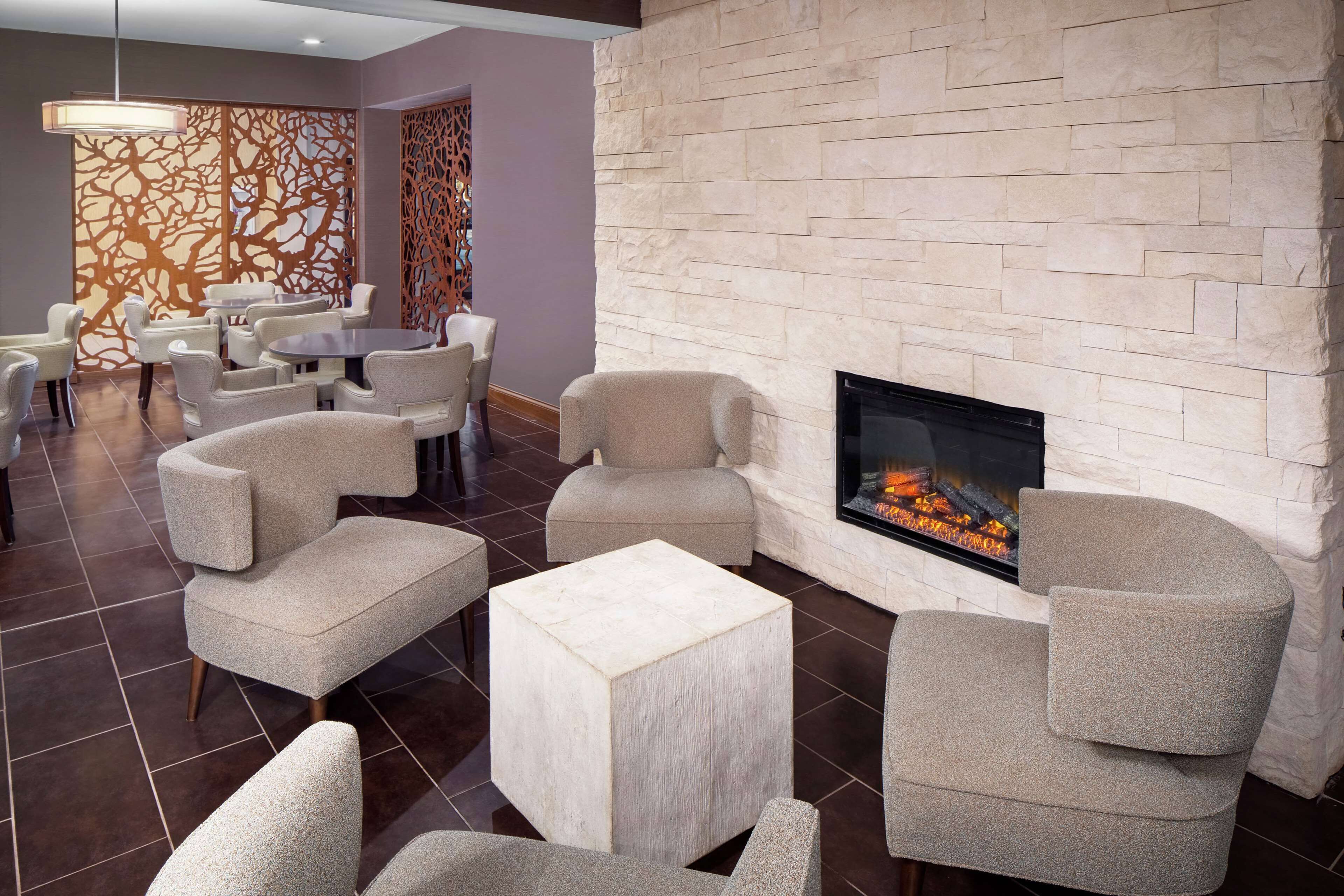 A modern lounge area with a stone fireplace, comfortable seating, and decorative panels.