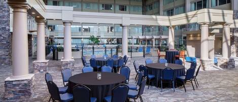 An indoor courtyard with round tables and chairs, a patterned floor, and a view of the building's interior.