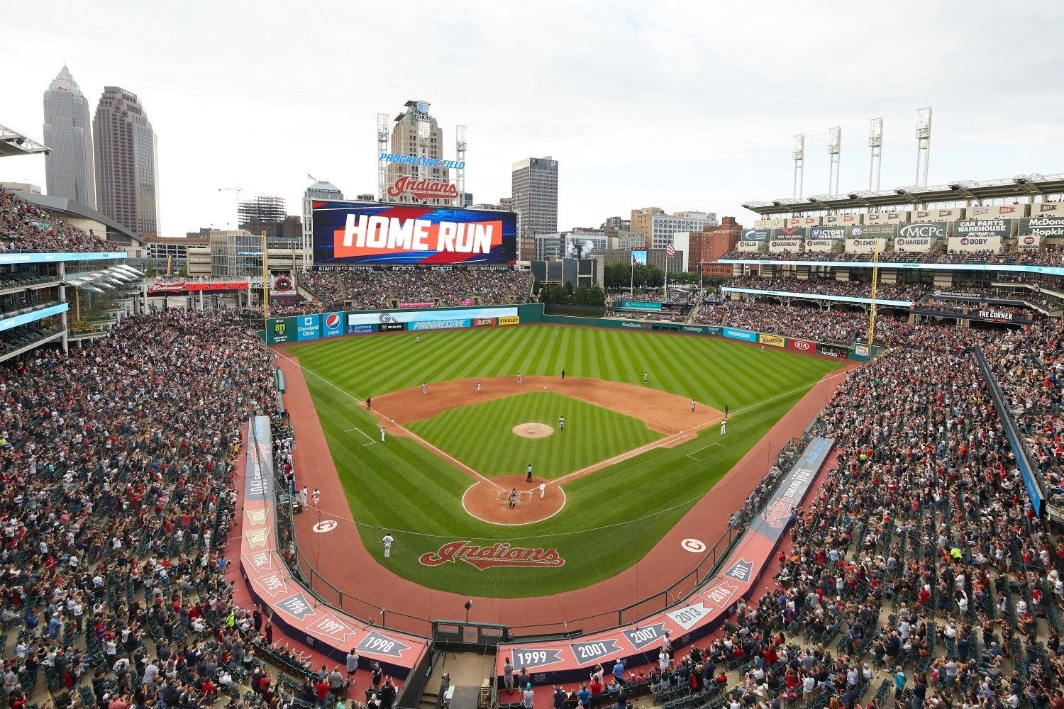 En baseballstadion med en stor publik, en resultattavla som visar ”HOME RUN” och Cleveland Indians logotyp.