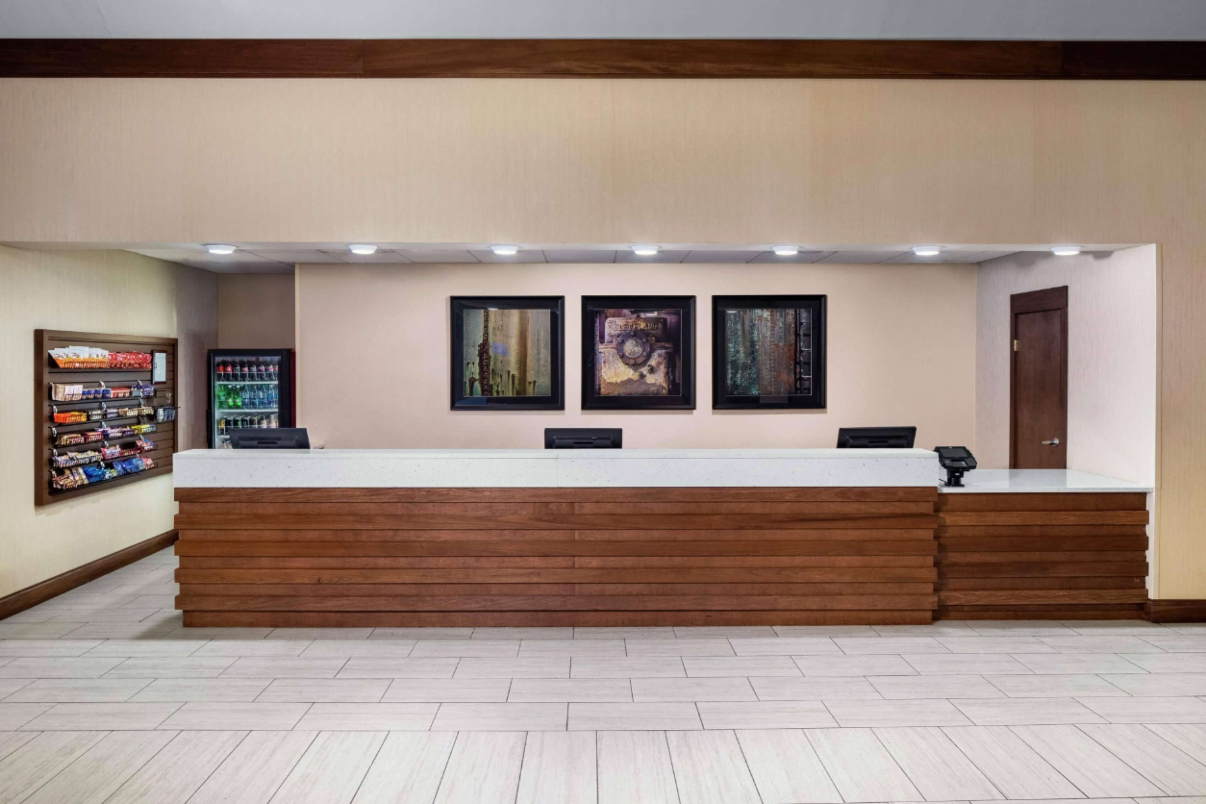 A reception desk with a wooden counter and three framed artworks above it.