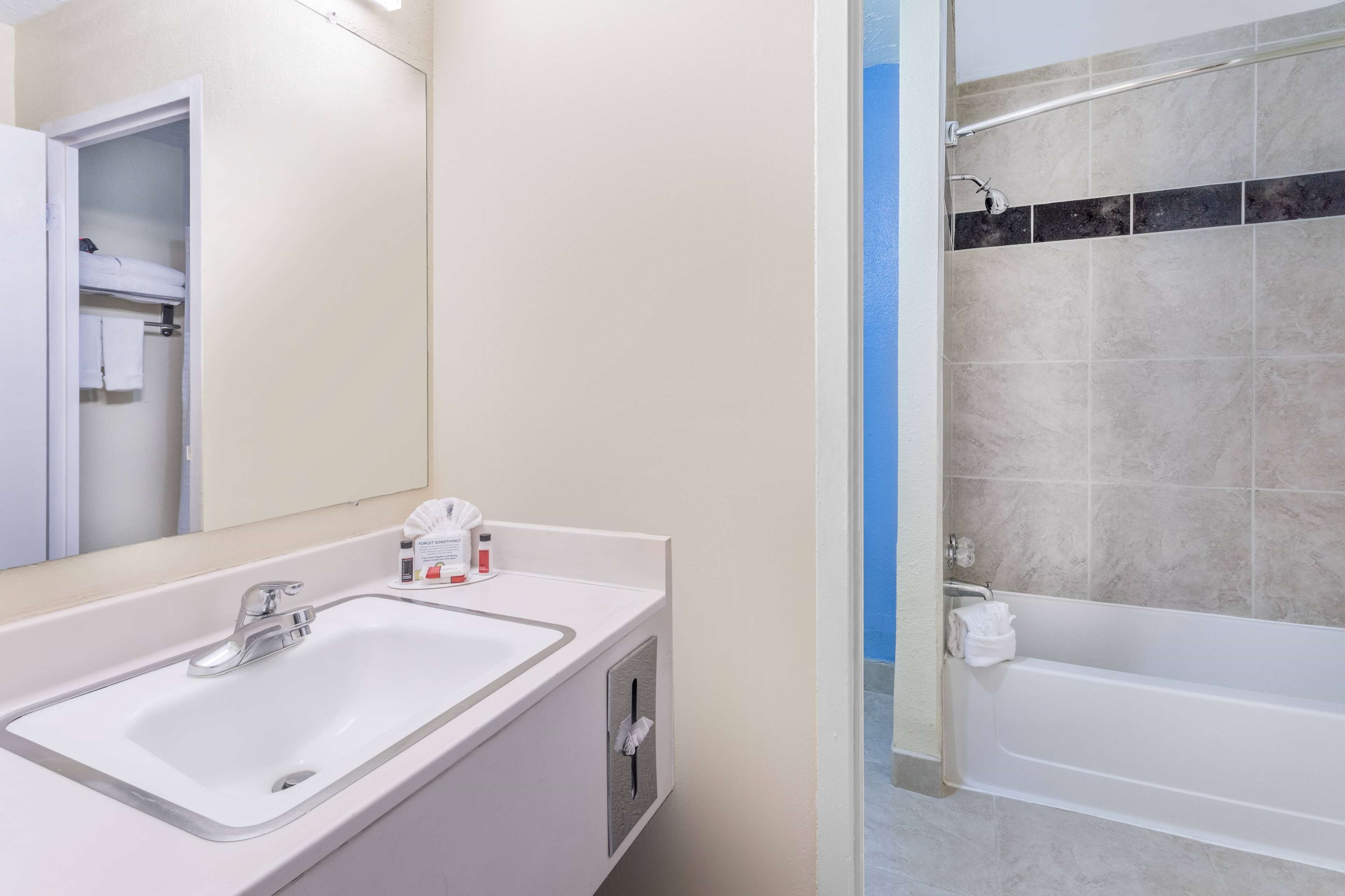 Un baño con lavamanos blanco, espejo y zona de ducha.