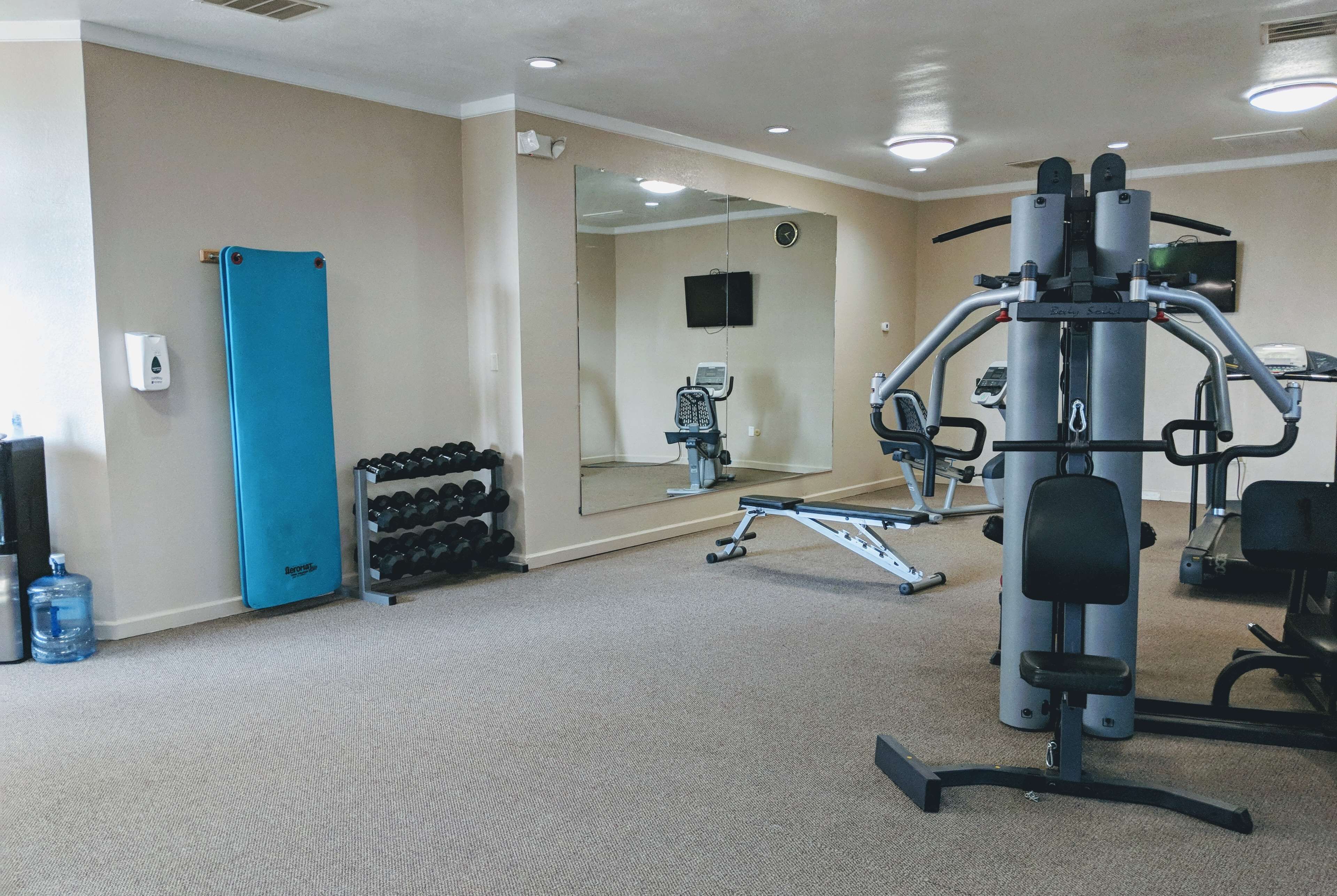 A gym with exercise equipment, a water dispenser, and a mirror.