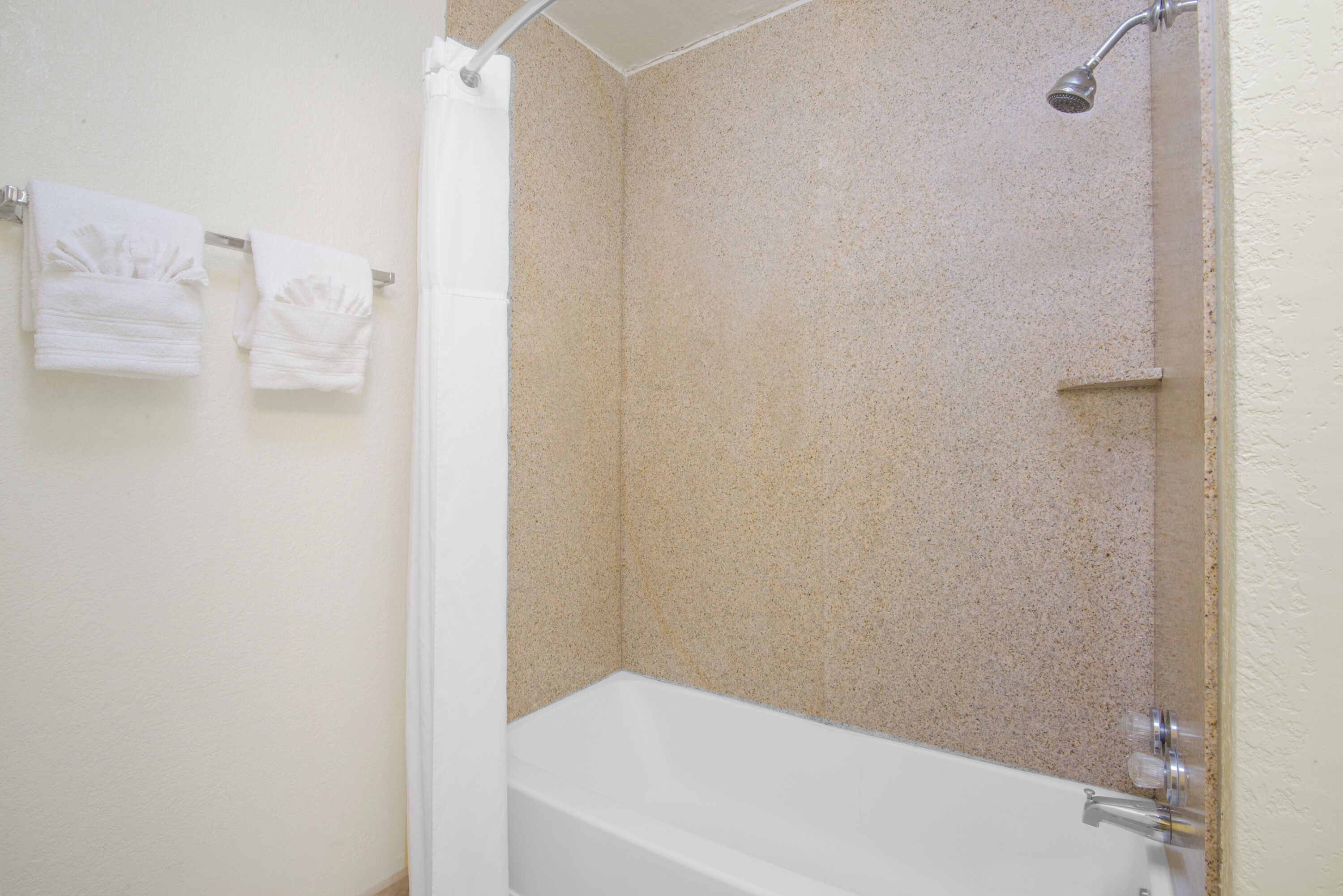 A bathroom with a bathtub, shower, and two towels hanging on the wall.