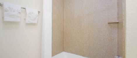 A bathroom with a bathtub, shower, and two towels hanging on the wall.