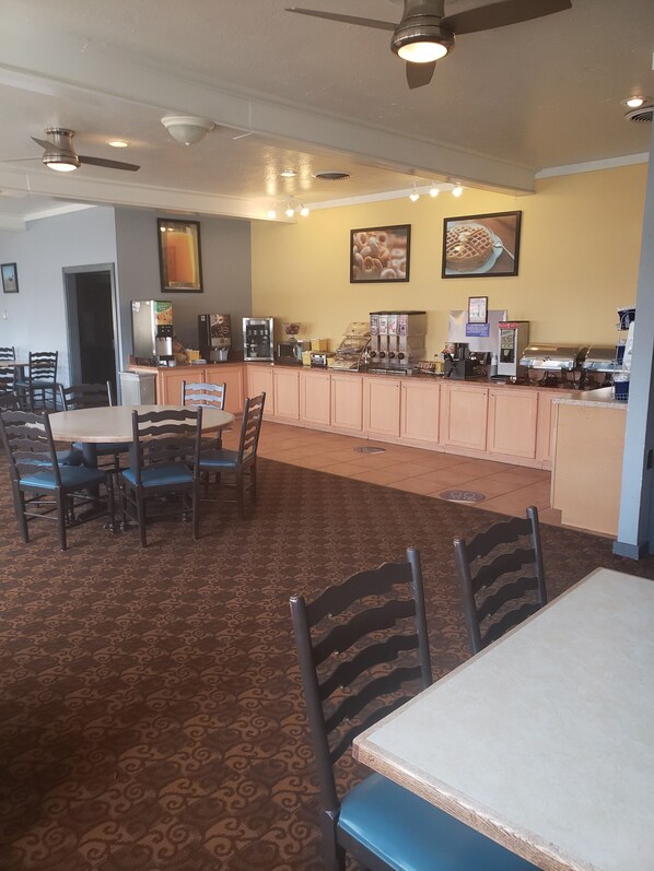 A restaurant with a counter, seating area, and ceiling fans.