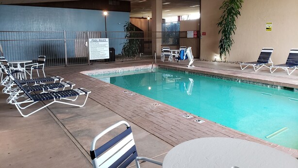 A pool area with lounge chairs and a sign detailing pool rules. - Days Inn & Suites by Wyndham Clovis (Clovis)