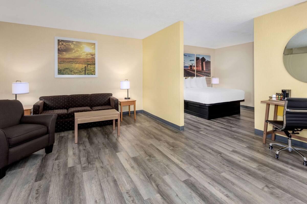 Quarto de hotel com sofá, cama, escrivaninha e cadeira.