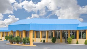 A hotel with a blue roof and yellow columns, featuring a covered outdoor area with windows and a parking lot. - Days Inn & Suites by Wyndham Clovis (Clovis)
