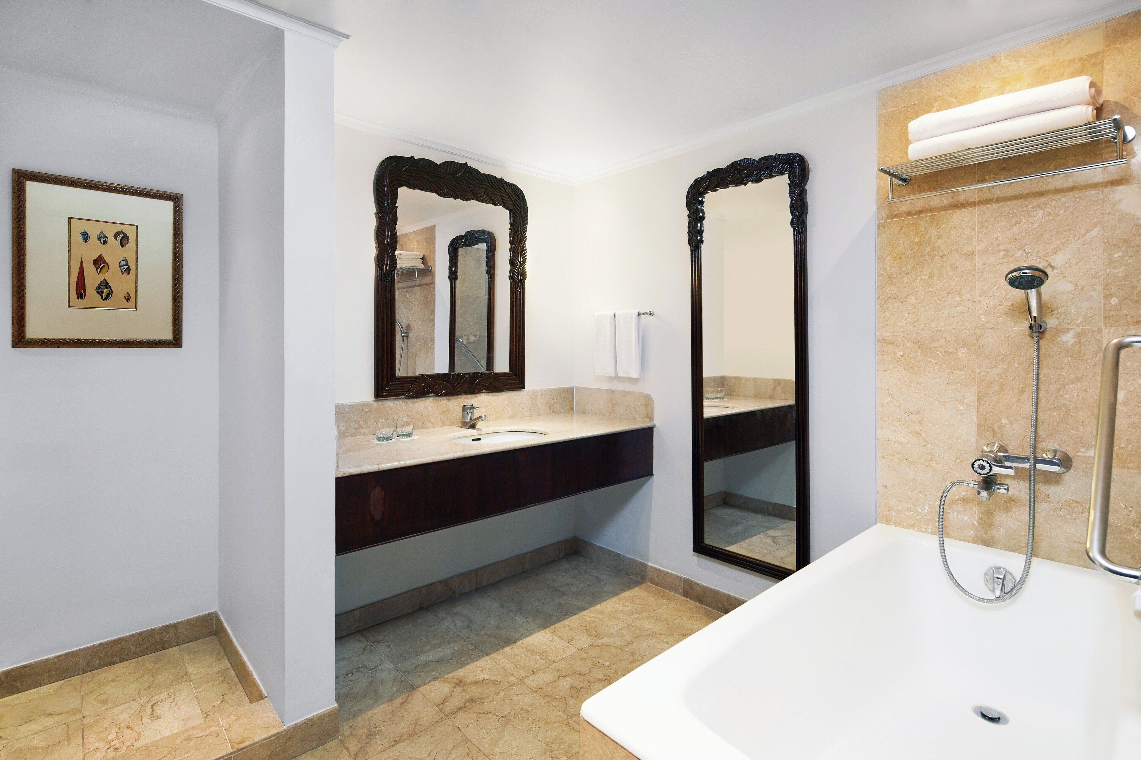 A modern bathroom with a large bathtub, a double vanity with a mirror, and a shower area.