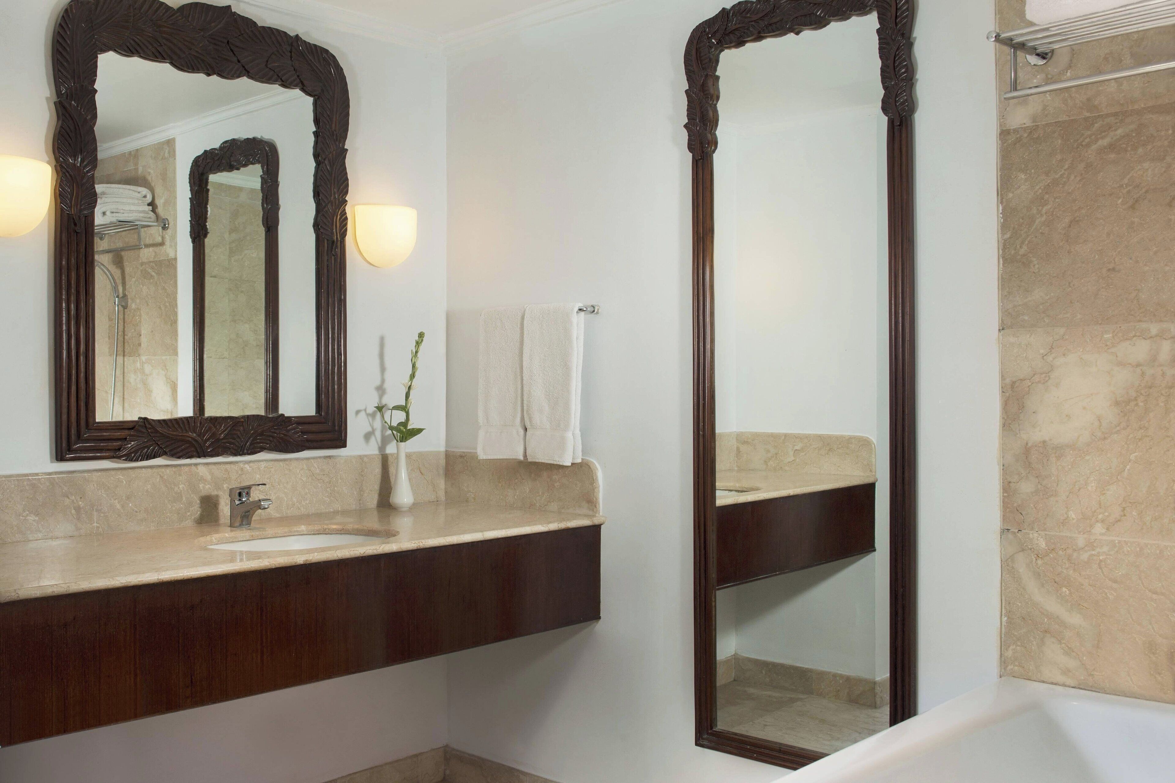 A bathroom with a dark wood vanity, a large mirror, a sink, and a bathtub.