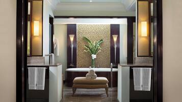 A modern bathroom with a bathtub, two sinks, and a bench.