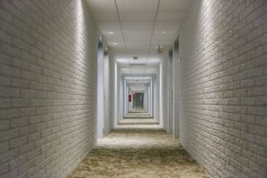 A long, narrow hallway with white brick walls and a patterned carpet. - Inns of Virginia - Arlington (Arlington)