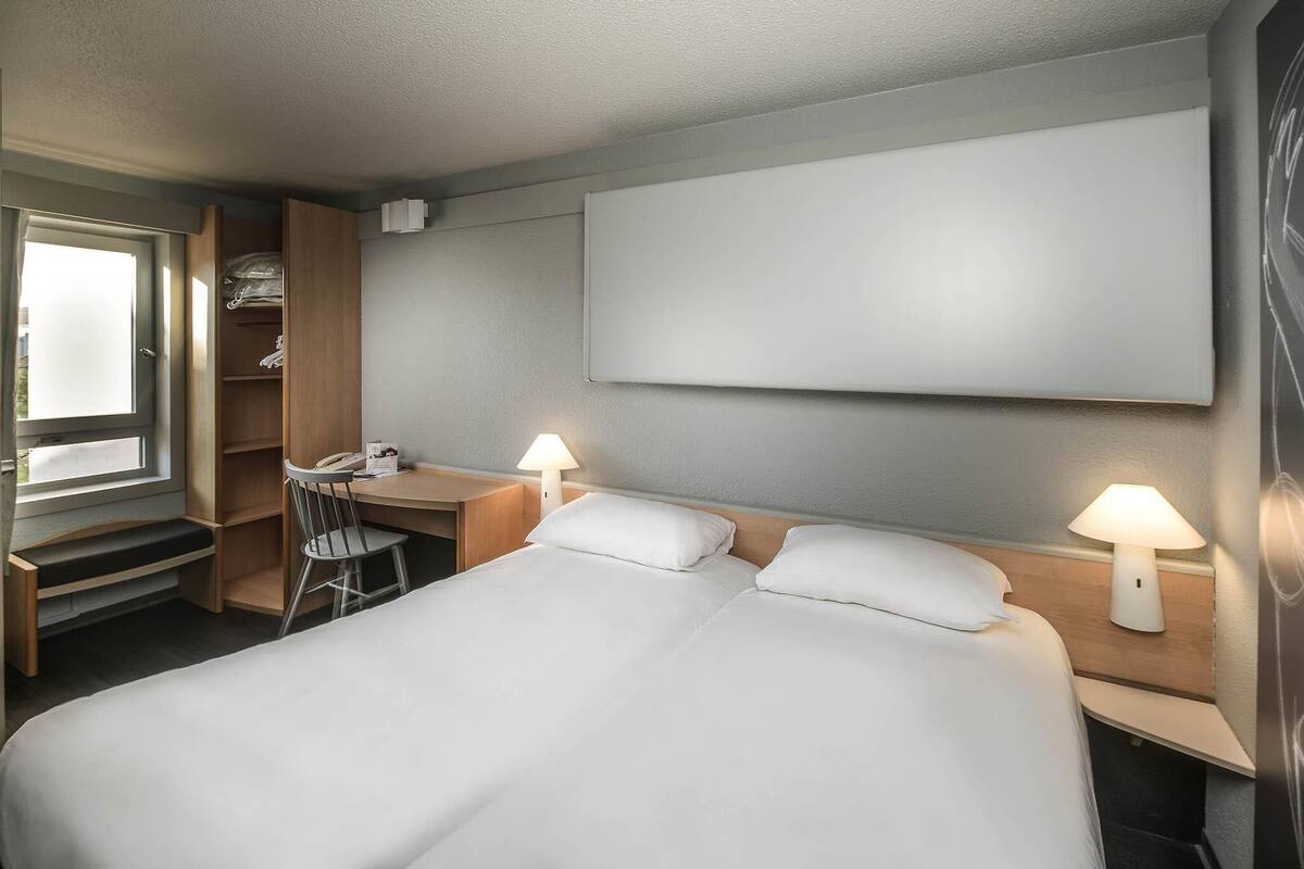 Une chambre d’hôtel comprenant un lit, un bureau, une chaise et une armoire.