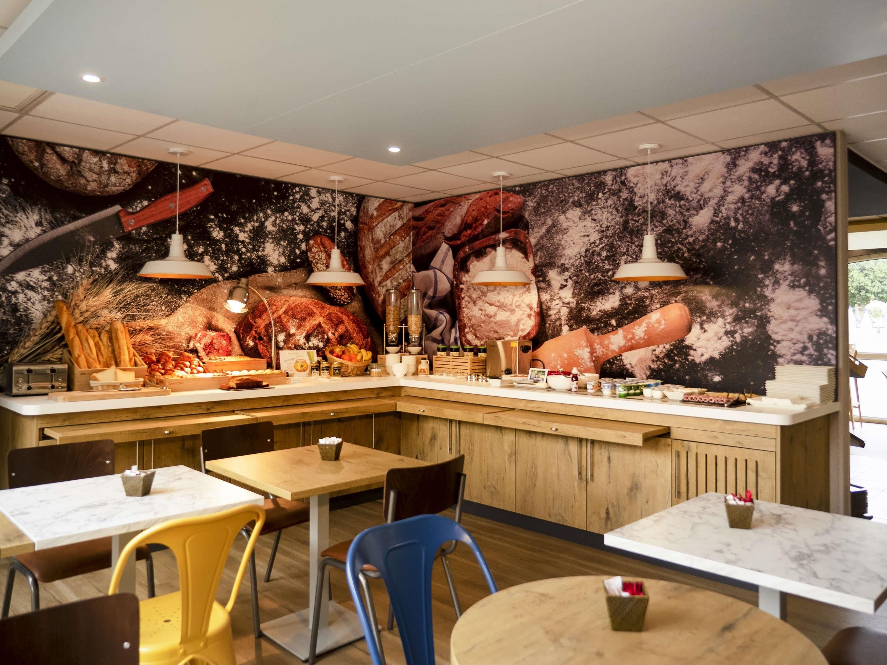 A restaurant with a central counter, multiple tables, and chairs.