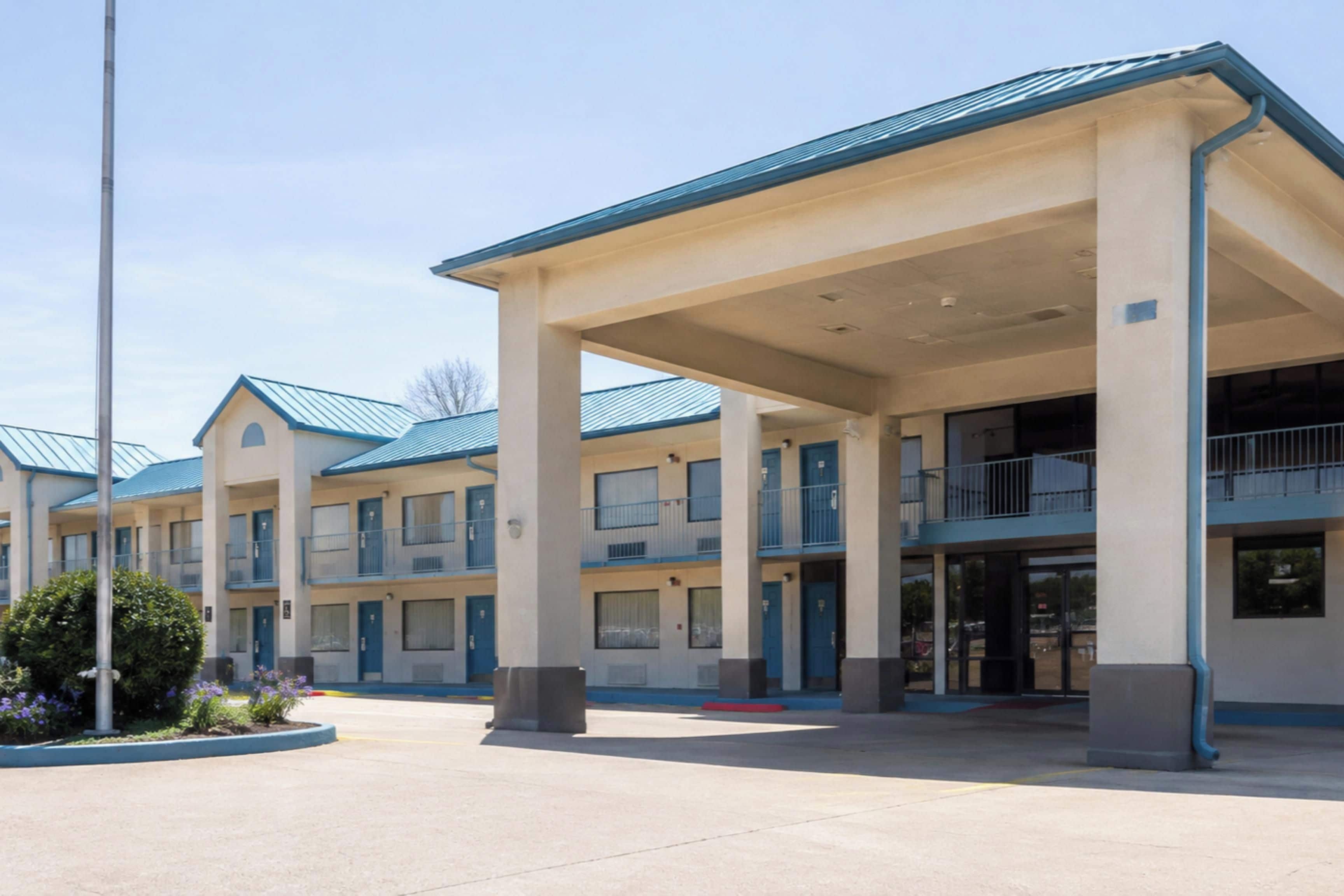 A multi-story motel with a central courtyard, featuring a series of balconies and a covered entrance area.