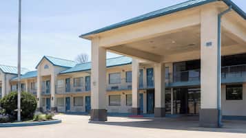 A multi-story motel with a central courtyard, featuring a series of balconies and a covered entrance area.