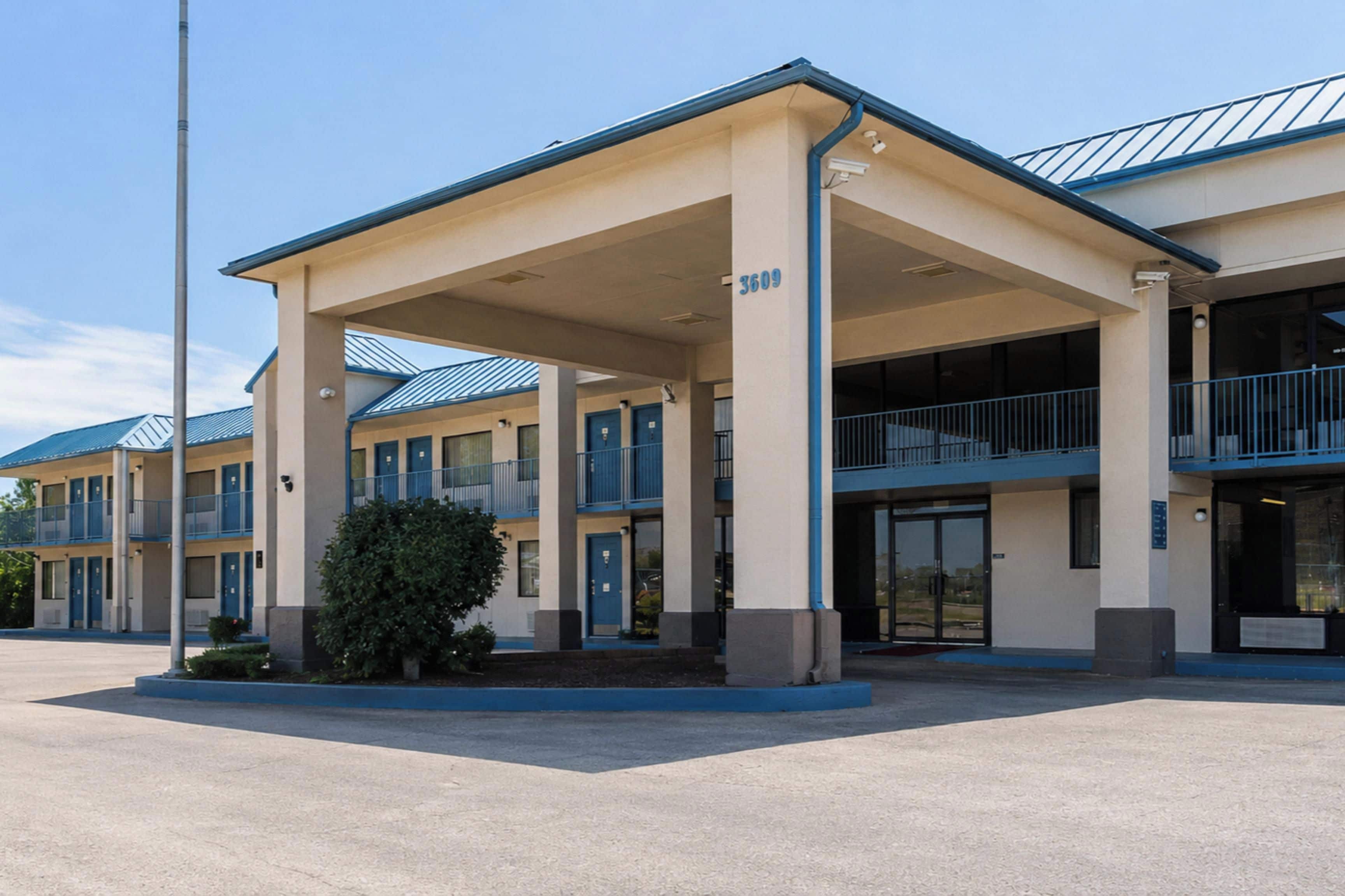 A multi-story motel with a covered entrance and a parking lot.